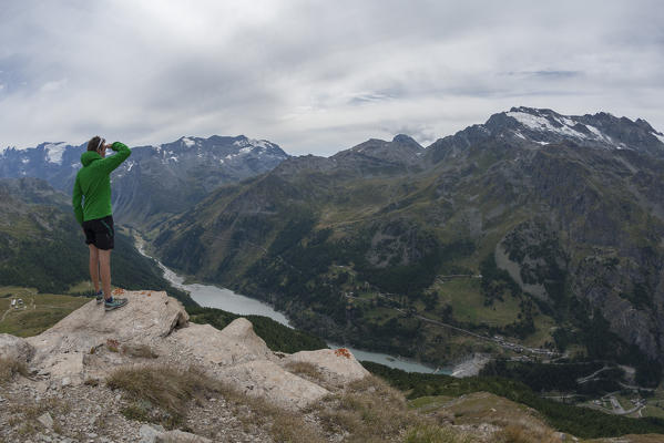 Hiker admires the Beauregard dam and the Rutor glacier, Valgrisenche, Aosta Valley, Italy