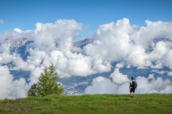 A man standing on the edge of an alp with the cloud covered Nordkette mountain range in the background, Patscherkofel mountain, Innsbruck, Tyrol, Austria, Europe