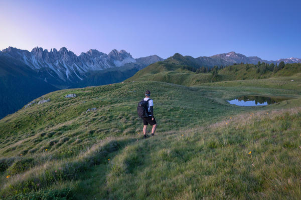 An Hiker admiring the landscape and the Kalkkögel mountain chain at early morning, Innsbruck Land, Tyrol, Austria, Europe