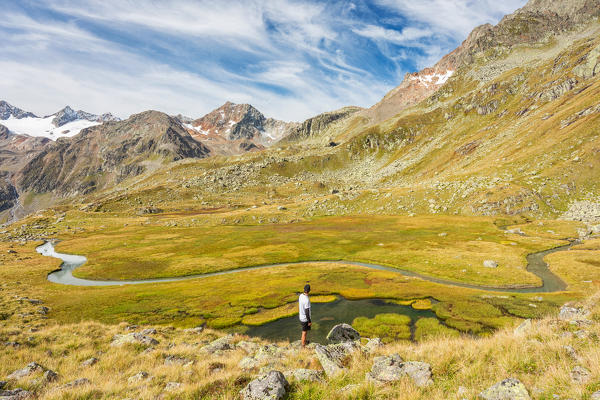 A man observes a wild stream crossing the meadows in the nearby of lake Mutterbergersee, Stubai Valley, Innsbruck Land, Tyrol, Austria, Europe