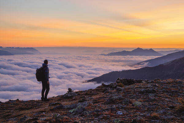 A Mountaineer enjoying the sunrise with the foggy Inn Valley and Kellerjoch mountain in the background, Patscherkofel mountain, Innsbruck Land, Tyrol, Austria, Europe 
