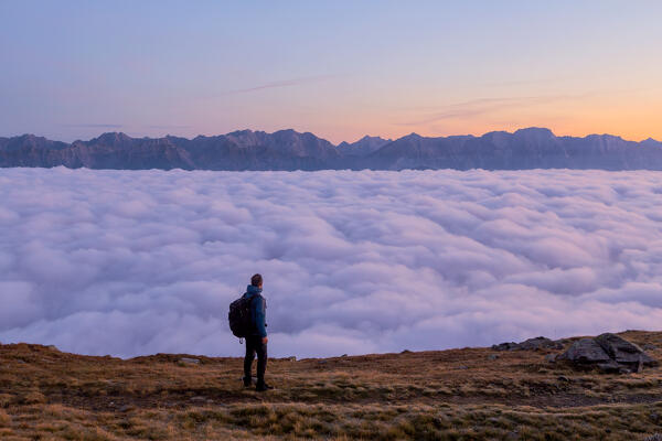 A Mountaineer staring at the foggy Inn Valley at dawn, Patscherkofel mountain, Innsbruck Land, Tyrol, Austria, Europe 