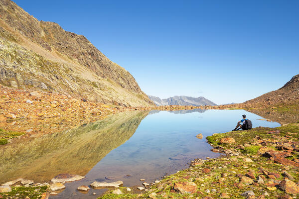 A mountaineer takes a break by Lake Freiger in the Stubai Alps, Langental Valley, Neustift im Stubaital, Innsbruck Land, Tyrol, Austria, Europe 