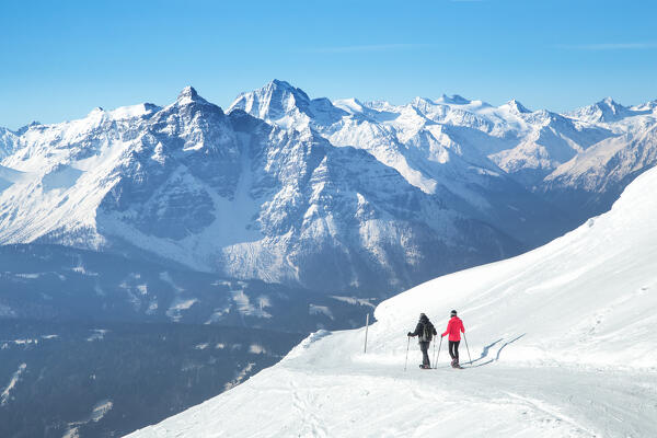 A couple of mountaineers snowshoeing with Stubai summits in the background, Patscherkofel Mountain, Innsbruck Land, Tyrol, Austria, Europe