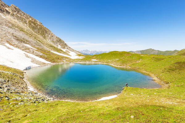 A mountaineer resting by Lake Ramsgrubner in Wildlahner, Toldern, Schmirn valley, Innsbruck Land, Tyrol, Austria, Europe