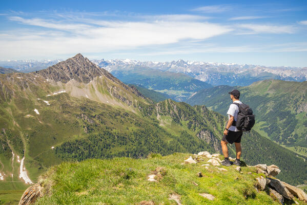 A mountaineer admiring the Hohe Warte mountain and the Stubai alps in the background from the Schoeberspitze mountain, Wildlahner, Schmirn Valley, Innsbruck Land, Tyrol, Austria, Europe