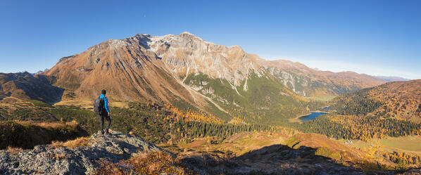 A mountaineer admiring the Obernberger Tribulaun and Lake Obernberg from a little summit in the nearby of Hoher Sattel on an autumn day, Obernberg am Brenner, Innsbruck Land, Tyrol, Austria, Europe