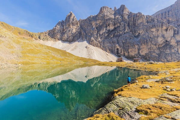 A hiker admiring the dolomitic rock formations of Tribulaun by the shore of Lago di Sanes - Lake Sandessee on a summer day, Ladurns, Bolzano district, South Tyrol, Italy, Europe