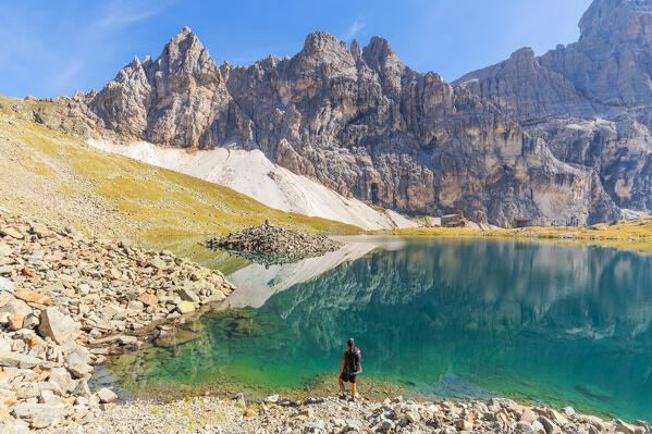 A hiker admiring the little island in the middle of Lake Sandessee - Lago di Sanes with the Tribulaun mountains in the background, Ladurns, Bolzano district, South Tyrol, Italy, Europe