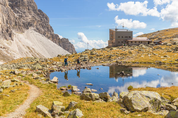 Reflection of two mountaineers hiking to Rifugio Calciati al Tribulaun on a summer day, Ladurns, Bolzano district, South Tyrol, Italy, Europe