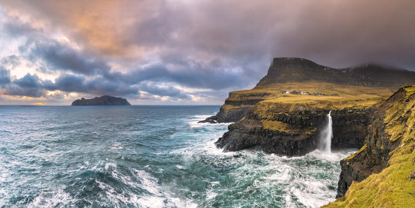 Gasadalur, the iconic waterfall of Múlafossur jumps down from the cliff into the ocean at sunset (Vagar Island, Faroe Islands, Denmark)