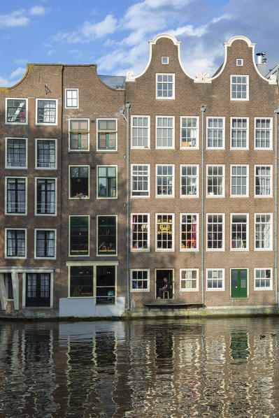 Typical houses reflected on canals in De Wallen district in Amsterdam (North Holland, Netherlands)