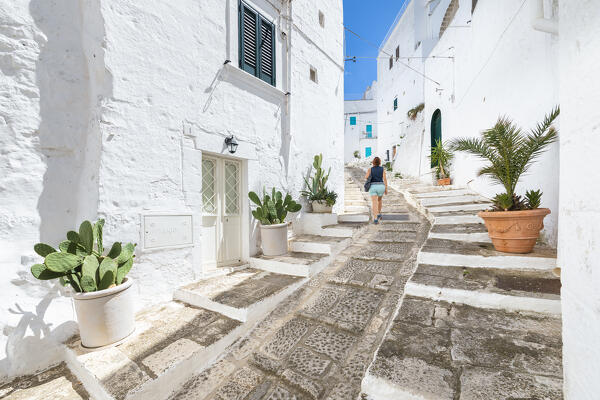 A woman is walking in a small street in the white village of Ostuni (province of Brindisi, Salento, Apulia, Italy) (MR)