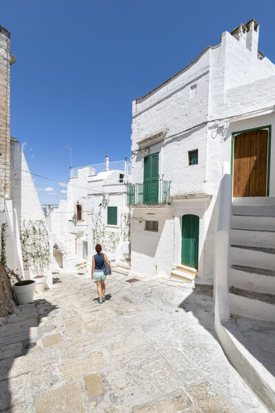 A woman is walking in a small street in the white village of Ostuni (province of Brindisi, Salento, Apulia, Italy) (MR)