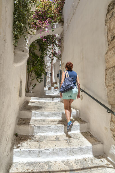 A woman is walking through the narrow alleys in the white village of Ostuni (province of Brindisi, Salento, Apulia, Italy) (MR)