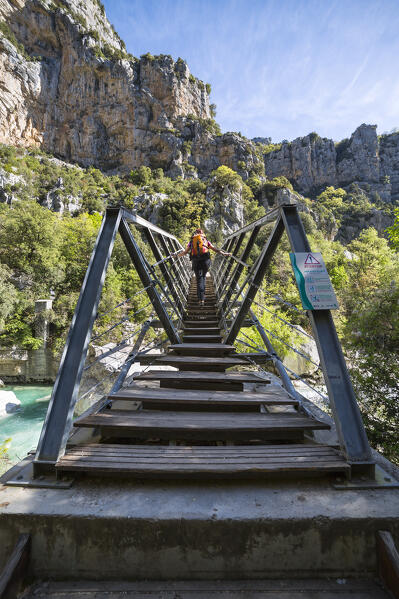 A female hiker is crossing the Verdon river on the Passerelle de l'Estellié in the Verdon Gorge (Var department, Provence-Alpes-Côte d'Azur, France, Europe) (MR)
