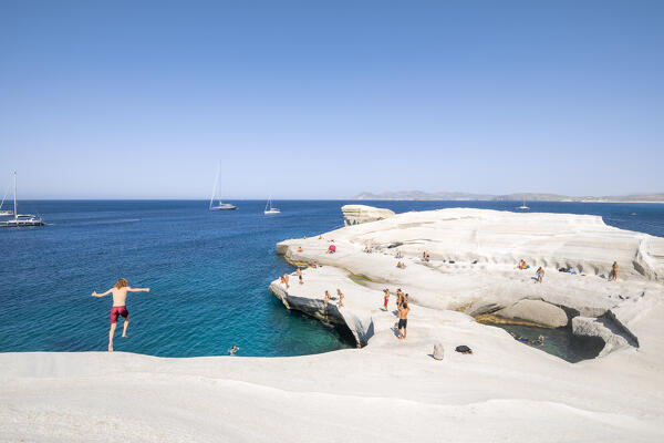 A boy dove from the top of the cliff on Sarakiniko Beach (Plaka, Milos Island, Cyclades Islands, Greece, Europe)