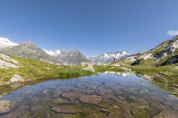 A woman is walking in front of Aletsch Glacier to Roti Chumme and Marjelensee (Bettmeralp, Bernese Alps, Canton of Valais, Switzerland, Europe) (MR)
