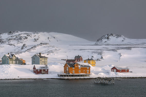 Some houses in the small village of Veines covered in snow during a cold winter sunrise (Kongsfjord, Varanger Peninsula, Troms og Finnmark, Norway)