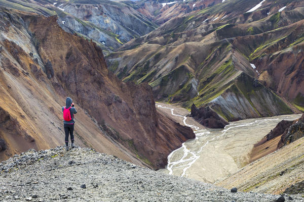 A trekker is taking a picture of the Landmannalaugar panorama from the footpath to the Blahnukur mountain (Landmannalaugar, Fjallabak Nature Reserve, Highlands, Southern Region, Iceland, Europe)