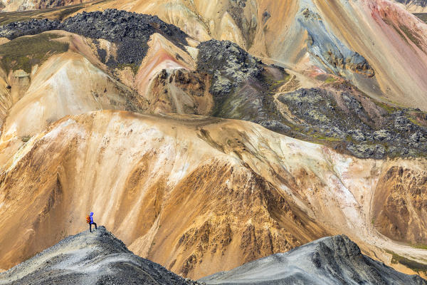 A trekker is looking at the Landmannalaugar panorama from Blahnukur mountain (Landmannalaugar, Fjallabak Nature Reserve, Highlands, Southern Region, Iceland, Europe) (MR)
