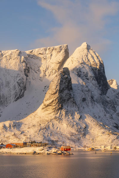 Red houses and mountains in Reine from the opposite side of the bay at sunrise. Reine, Lofoten island, Norway, Scandinavia, Europe.
