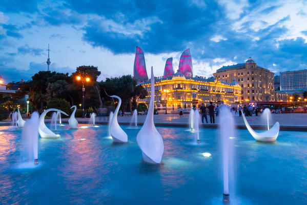 A swans fountain in the Baki Bulvari with Flame Towers in the background at twilight. Baku, Azerbaijan, Central Asia.