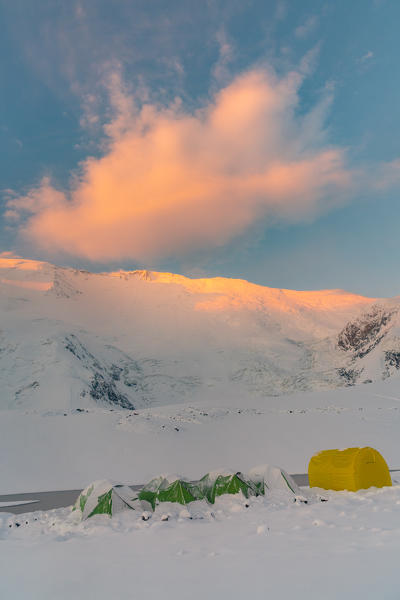 The yurts and tents of peak Lenin camp one at sunrise with Peak Lenin massif in the background. Pamir, Kyrgyzstan, Central Asia. 