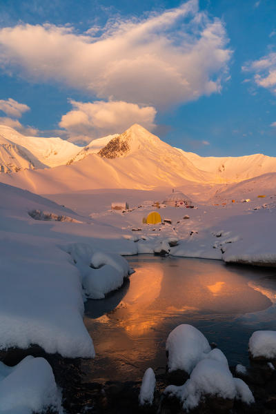 The yurts and tents of peak Lenin camp one at sunrise with Peak Lenin massif in the background. Pamir, Kyrgyzstan, Central Asia. 