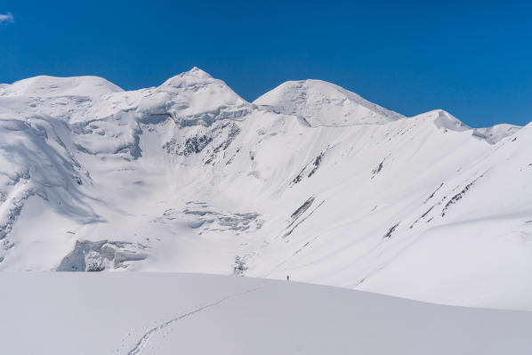 Ski mountaneering to Yuhina peak with Peak Lenin massif and glacier in the background. Pamir, Kyrgyzstan, Central Asia. 