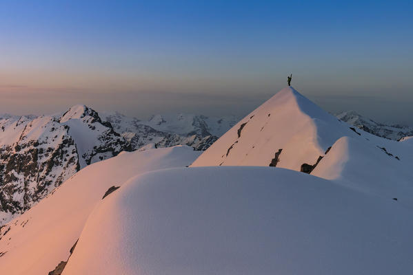 Ski mountaneer in the summit of Punta degli Spiriti, Geister spitze with the sunrise red light in the snowcapped ridge. Stelvio pass, Stilfser joch, Bormio, SOndrio district, Alps, Lombardy, Italy, Europe.