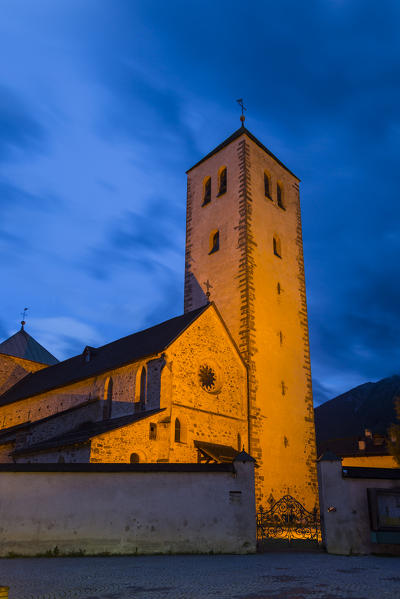 The medioeval Collegiata dei Santi Candido and Corbiniano church and its bell tower illuminated at dusk in the Dolomites mountain village of San Candido. San Candido, Pusteria valley, Bolzano district, Dolomites, Trentino Alto Adige, Italy, Europe.