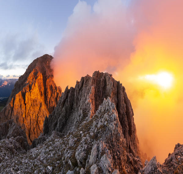 Cloudy sunset with Roda de Vael peak illuminated and backlight red clouds from the rocks of Vajolon pass. Roda de Vael refuge, Carezza pass, Fassa valley, Trento district, Dolomites, Trentino Alto Adige, Italy, Europe.