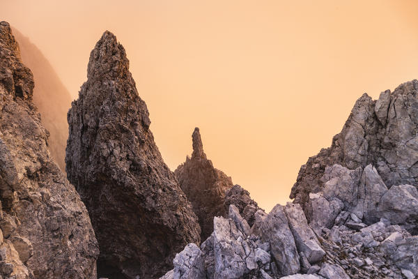 Rock spurs during a cloudy sunset in backlight under Roda de Vael mount in Catinaccio group. Carezza, Fassa valley, Trento district, Dolomites, Trentino Alto Adige, Italy, Europe.
