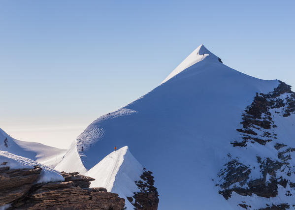 Lyskamm snow ridge under blue sky with alpinists climbing the ridge. Gressoney, Aosta district, Valle d'Aosta, Alps, Italy, Europe.