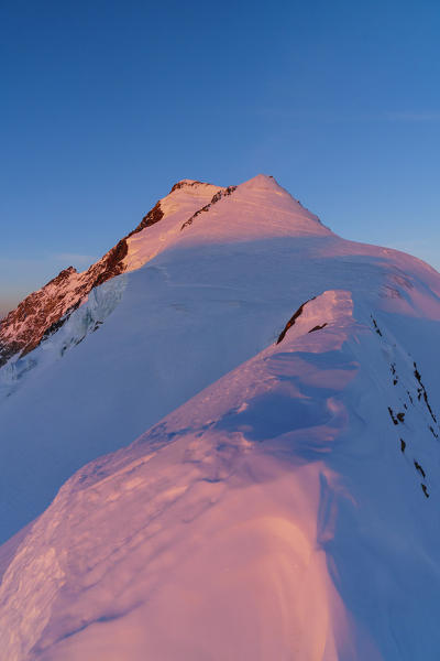 High mountains landscape of the summit of Aletschorn at sunrise from the normal route snow ridge. 