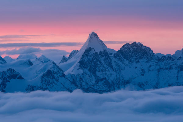 Dent d'Herens peak over a clouy carpet during a winter sunrise. Igloo refuge des Pantalons Blancs, Heremence, Sion, Valais canton, Switzerland, Europe.