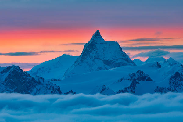 Mountainscape of Matterhorn peak over a clouy carpet during a winter sunrise. Igloo refuge des Pantalons Blancs, Heremence, Sion, Valais canton, Switzerland, Europe.