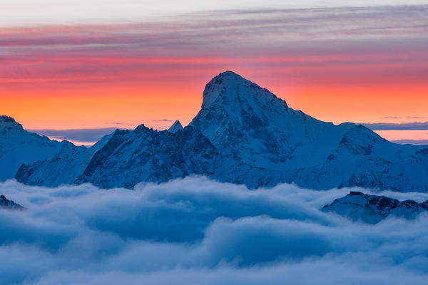 Dent Blanc peak over clouds during a winter sunrise in Swiss Alps. Igloo refuge des Pantalons Blancs, Heremence, Sion, Valais canton, Switzerland, Europe.