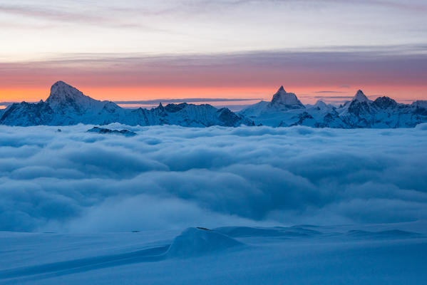 Mountainscape with 4000 of Valais over a clouy carpet during a winter sunrise. Igloo refuge des Pantalons Blancs, Heremence, Sion, Valais canton, Switzerland, Europe.