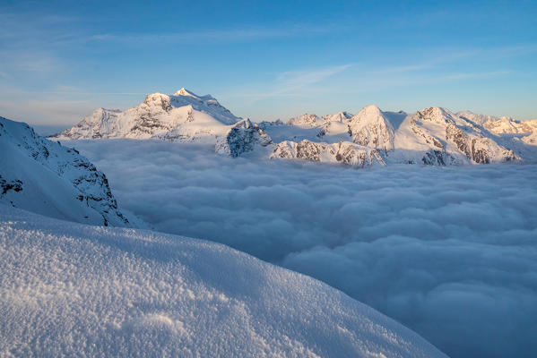 Mountainscape of Grand Combin mount over clouds from La Sale peak during winter. Igloo refuge des Pantalons Blancs, Heremence, Sion, Valais canton, Switzerland, Europe.