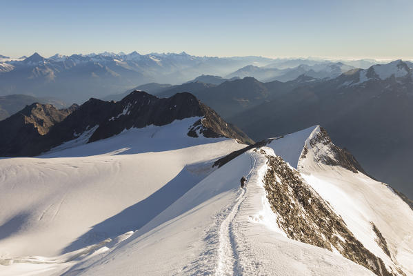Alpinist along the ridge to Nadelhorn, a 4000 peak in Sass Fe valley. Sass Fe, Vallese canton, Switzerland, Alps, Europe.