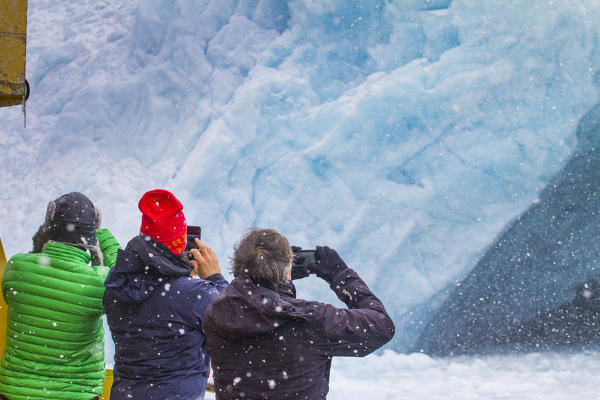 Tourists looking the sea ice glacier from a boat. West coast of Greenland, Artic sea, Denmark