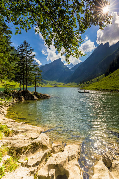 Sunny day at Seealpsee with boat in silhouette, Canton of Appenzell, Alpstein, Switzerland, Europe