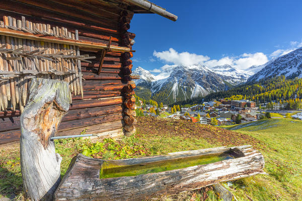 Traditional fountain with view on the alpine village. Arosa, Canton of Graubunden, Switzerland.