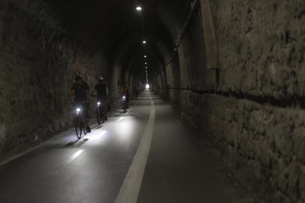 Four cyclists ride through one of the tunnels of the bike path around Lerici. Gulf of La Spezia, La Spezia province, Liguria, Italy, Europe