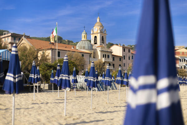 Umbrellas closed on the beach in front of San Terenzo church, Lerici, Gulf of La Spezia, La Spezia province, Liguria, Italy, Europe