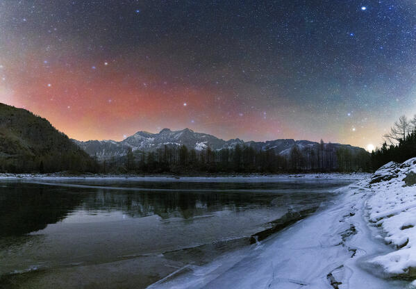 Night view of the frozen Lagazzuolo lake with northern light in the sky.  Valtellina,Valmalenco, Lombardy, Italy, Europe.