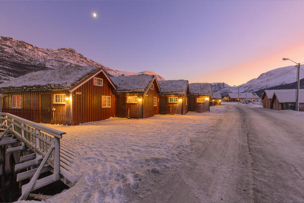 Traditional fishing houses used as accommodation for tourists during twilight. Lokvoll, Manndalen, Kafjord, Lyngen Alps, Troms, Norway, Lapland, Europe.