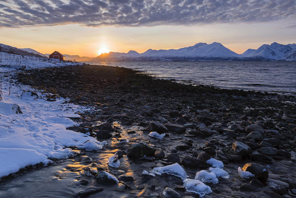 The sun sets behind the Lyngen Alps. Nordmannvik, Kafjord, Lyngen Alps, Troms, Norway, Lapland, Europe.